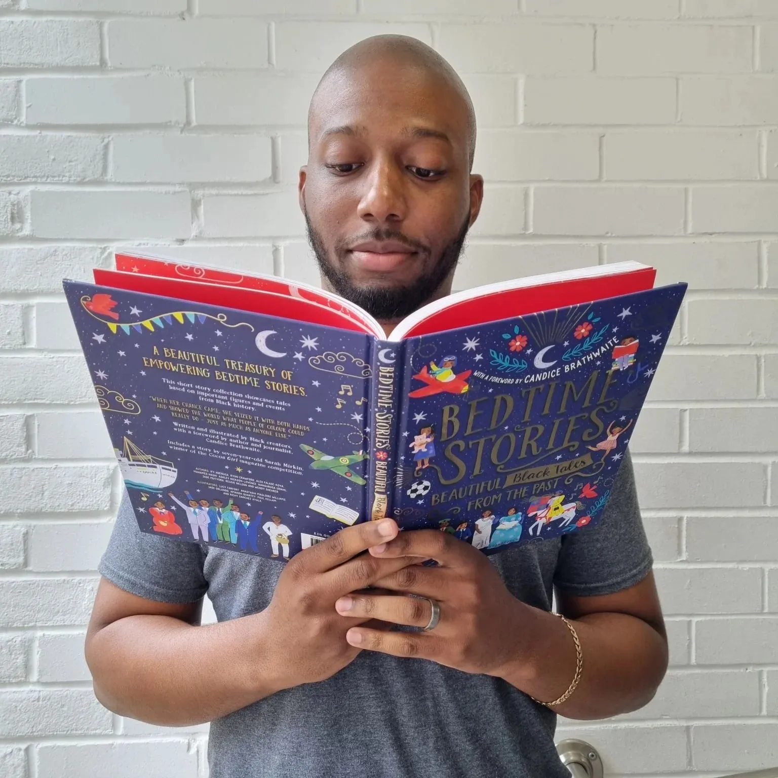Ryan Crawford reading the book, open at a full-colour spread