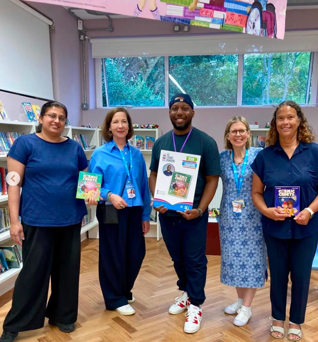 Ryan Crawford with the Burnt Ash Library team, holding a GLL Literary Foundation board and Cosmic Cadets